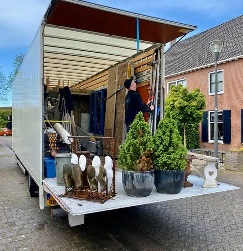 Geopende verhuiswagen met inboedel en planten